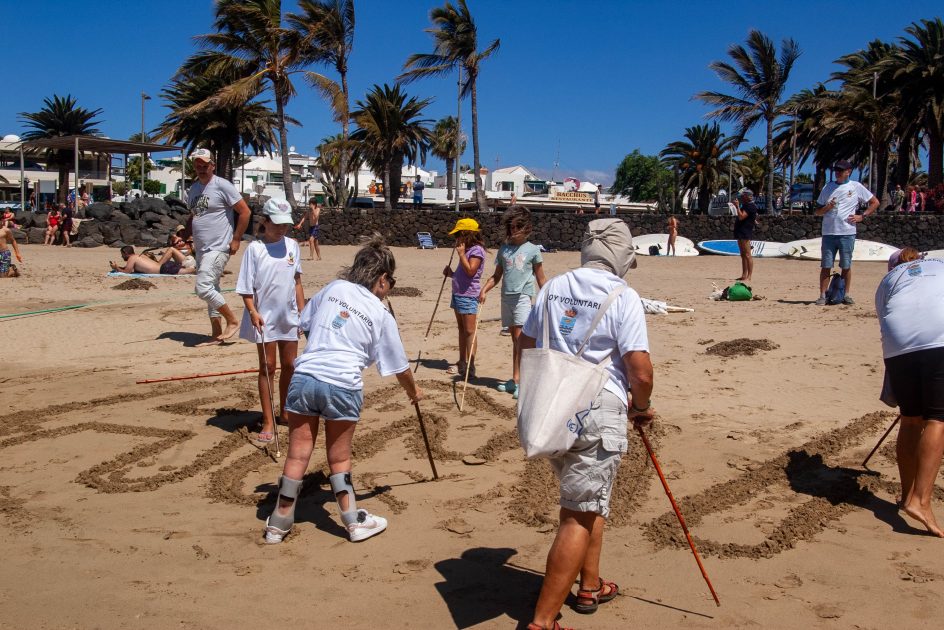 Voluntarios y jóvenes de ADISLAN participando en la jornada de limpieza y surf inclusivo en la Playa de Las Cucharas, Costa Teguise.