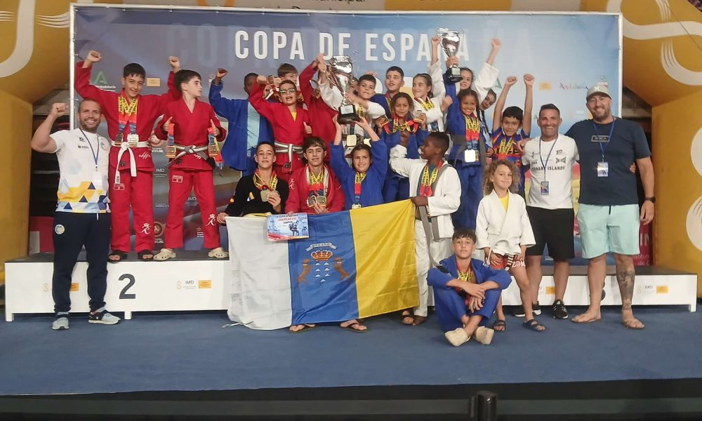 Deportistas del club TAZ Lanzarote posando juntos con sus medallas de oro, plata y bronce en el tapiz de grappling