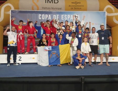 Deportistas del club TAZ Lanzarote posando juntos con sus medallas de oro, plata y bronce en el tapiz de grappling