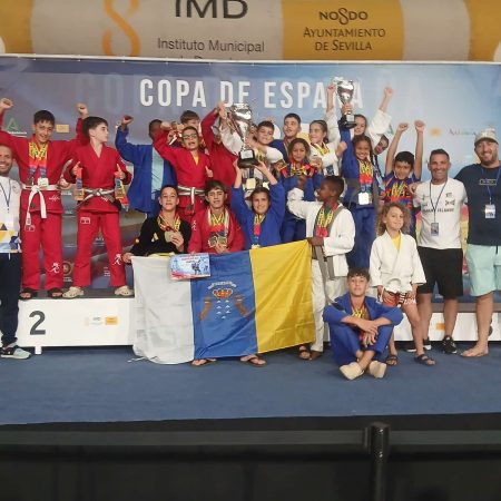 Deportistas del club TAZ Lanzarote posando juntos con sus medallas de oro, plata y bronce en el tapiz de grappling