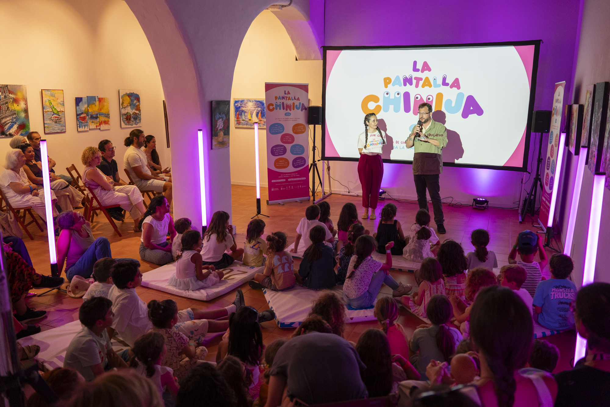 Niños y niñas sentados en el suelo participando en un debate con la mediadora Vicki Dos Santos en el Centro Sociocultural de La Graciosa.