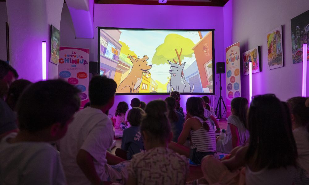 Niños y niñas sentados en el suelo participando en un debate con la mediadora Vicki Dos Santos en el Centro Sociocultural de La Graciosa.