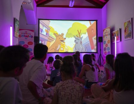Niños y niñas sentados en el suelo participando en un debate con la mediadora Vicki Dos Santos en el Centro Sociocultural de La Graciosa.