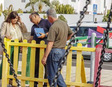 Operarios municipales instalando pavimento amortiguador de caucho en un parque infantil de Teguise.