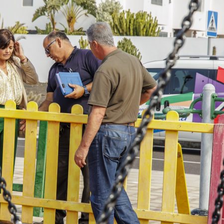 Operarios municipales instalando pavimento amortiguador de caucho en un parque infantil de Teguise.