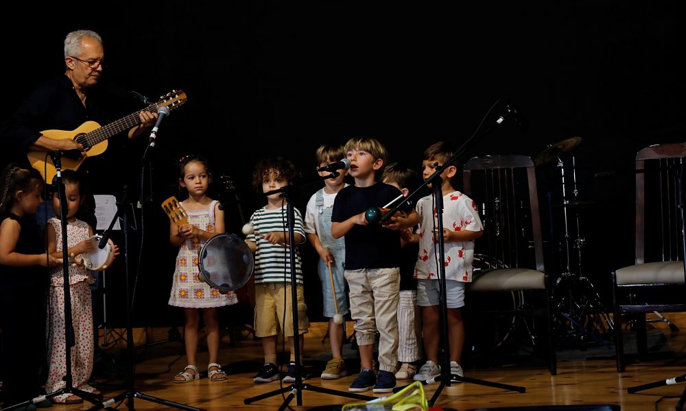 Alumnado infantil junto a Toñín Corujo sobre el escenario del Teatro Chico Cuatro Esquinas
