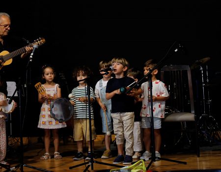 Alumnado infantil junto a Toñín Corujo sobre el escenario del Teatro Chico Cuatro Esquinas