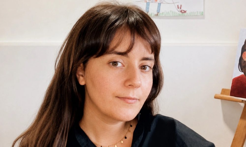 Retrato de la escritora lanzaroteña Lana Corujo sosteniendo su novela de éxito internacional.