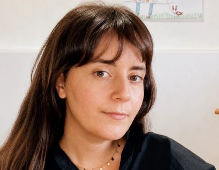 Retrato de la escritora lanzaroteña Lana Corujo sosteniendo su novela de éxito internacional.