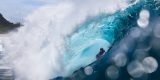 Primer plano de la fotógrafa marina Christa Funk nadando entre grandes olas con su cámara de agua en Hawái.