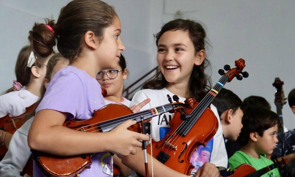 Jóvenes tocando instrumentos de cuerda en una clase del proyecto Barrios Orquestados.