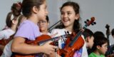 Jóvenes tocando instrumentos de cuerda en una clase del proyecto Barrios Orquestados.