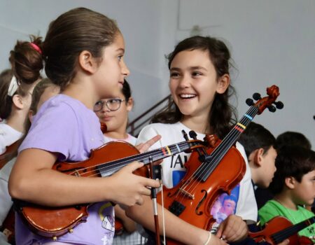 Jóvenes tocando instrumentos de cuerda en una clase del proyecto Barrios Orquestados.