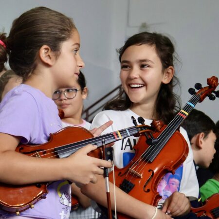 Jóvenes tocando instrumentos de cuerda en una clase del proyecto Barrios Orquestados.